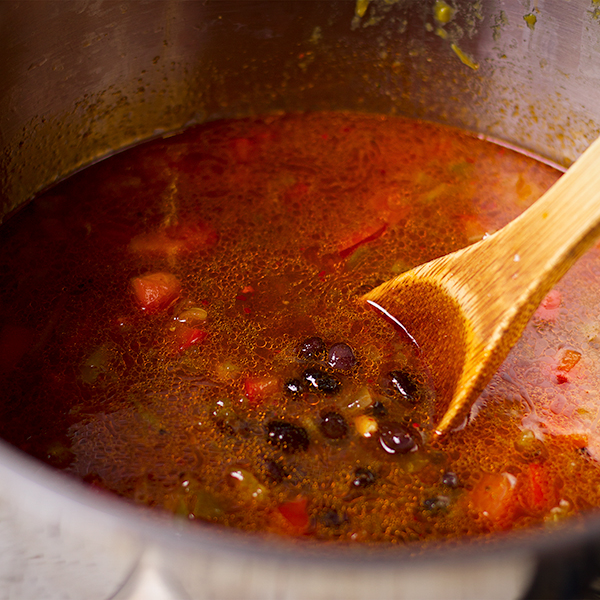 Stirring a pot of black bean soup.