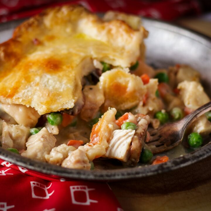 A piece of double crust chicken pot pie on a tin plate.