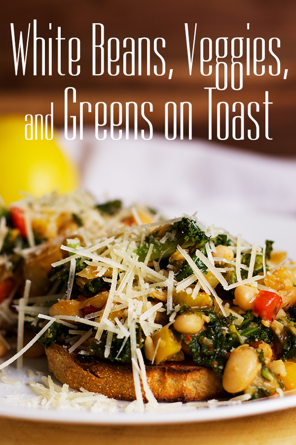 A plate with two slices of toast topped with white beans, veggies and greens, sprinkled with grated parmesan cheese.