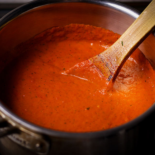 Stirring a pot of creamy red pepper sauce.