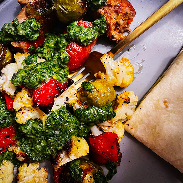 A sheet pan dinner with Italian Sausage, Vegetables, and Chimichurri Sauce, served with a homemade flour tortilla.