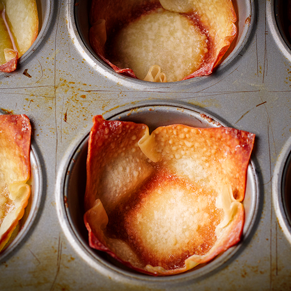 Freshly baked crispy wonton shells in a muffin tin.