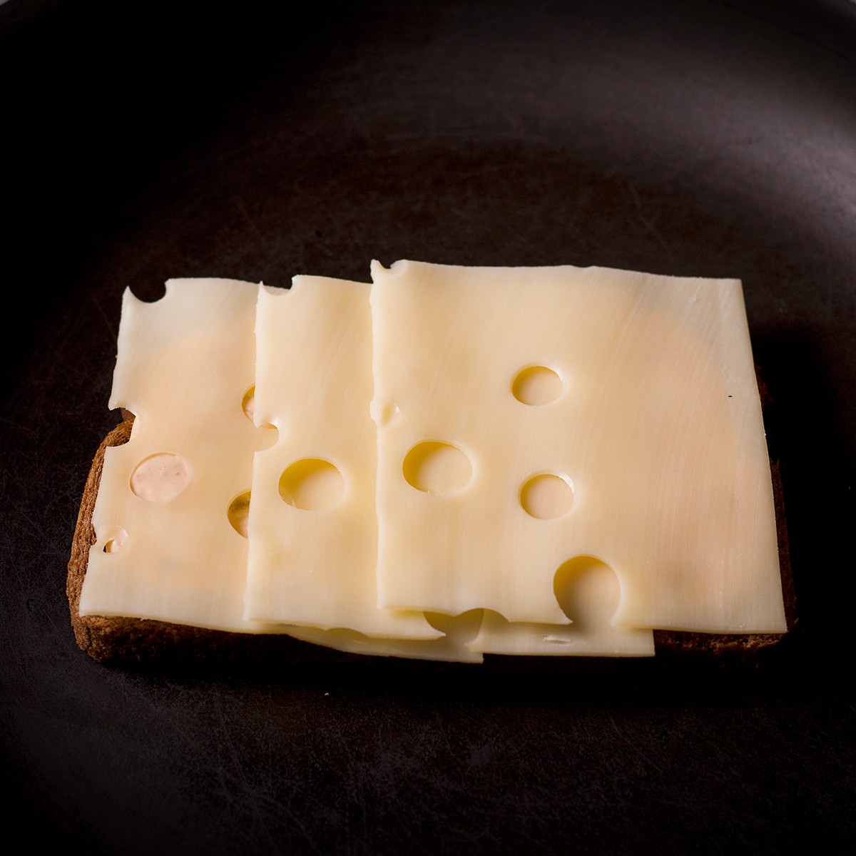 A piece of Rye bread spread with Russian dressing and layered with Swiss cheese in a skillet.