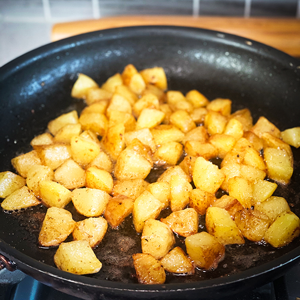 Cooking crispy fried potatoes in a skillet.