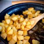 Cooking crispy fried potatoes in a skillet.