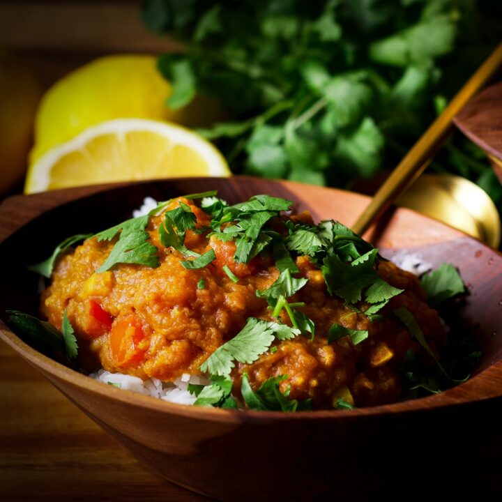 A wood bowl containing red lentil dal over rice.