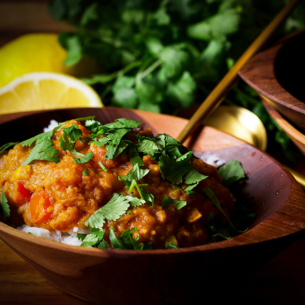 A wood bowl filled with rice and homemade red lentil dal.