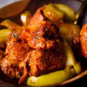 A wood bowl filled with Spanish pork bites and brown sugar and butter fried apples.