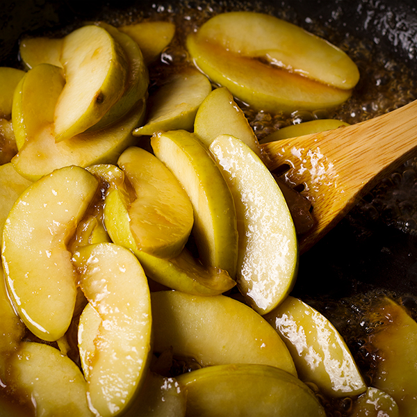 Stirring fried apples in a hot skillet.