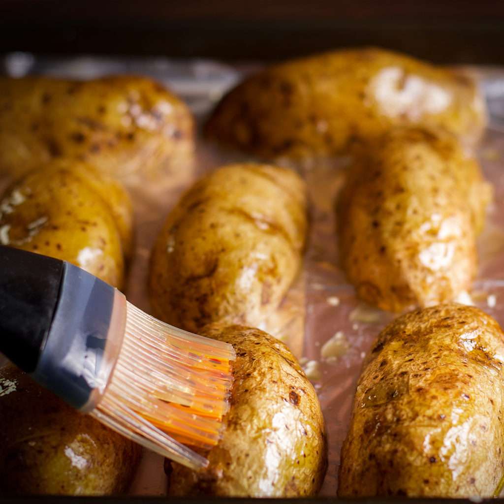 Using a pastry brush to coat potato skins with sesame and olive oil before baking.