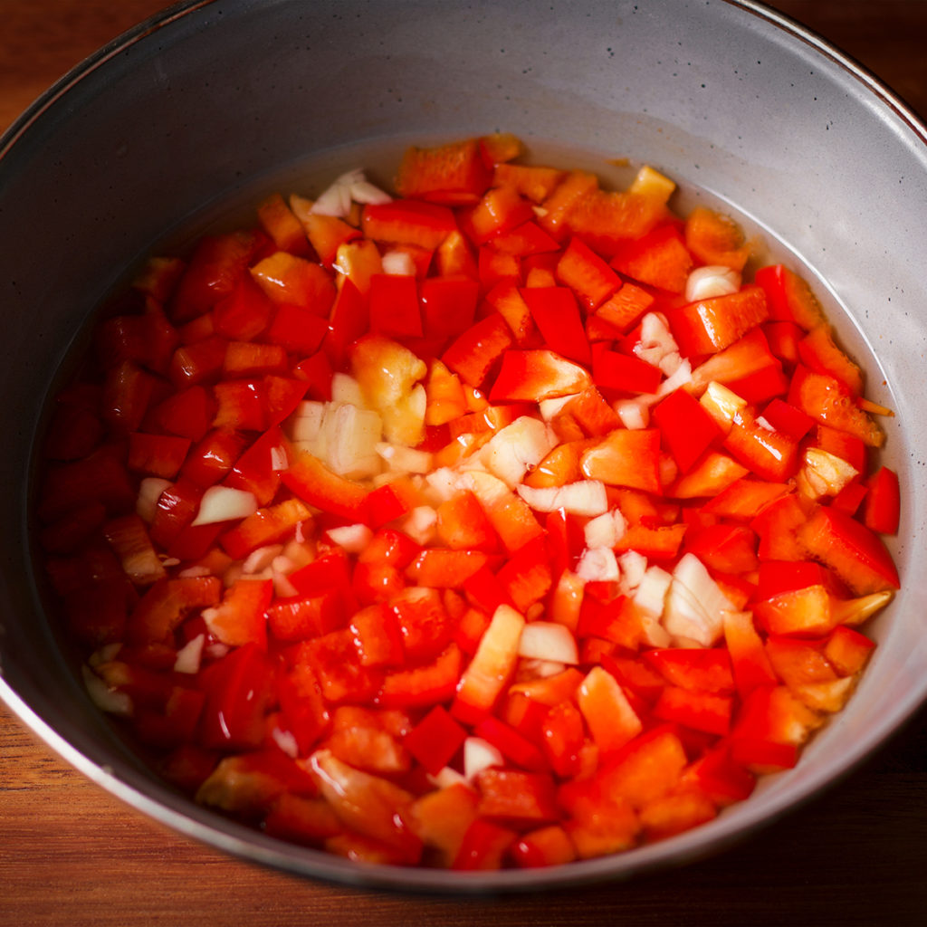 A bowl of pickled red bell peppers and garlic.