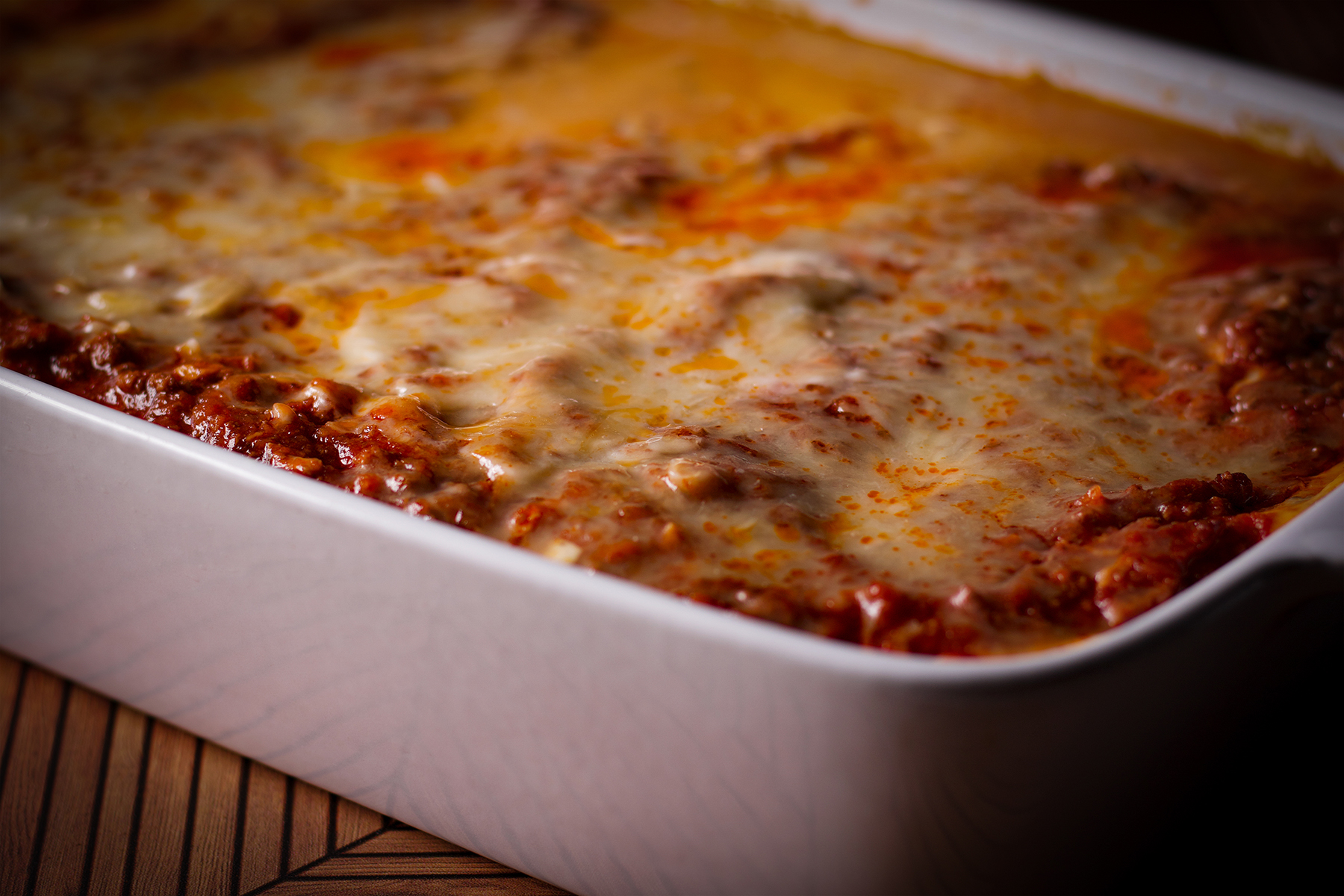Freshly baked lasagna bolognese in a white casserole dish.