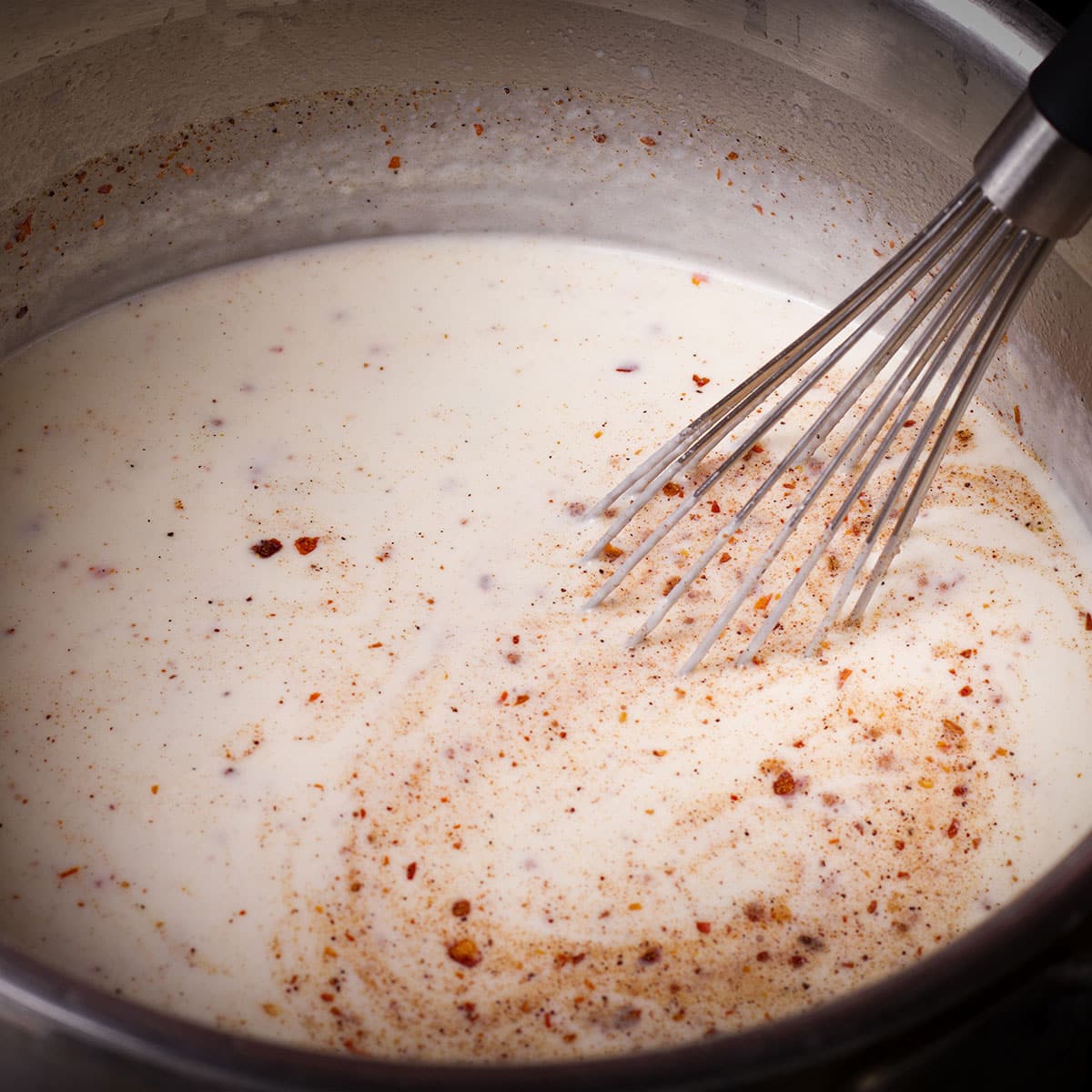 Stir nutmeg and crushed red pepper flakes into the bechamel sauce.