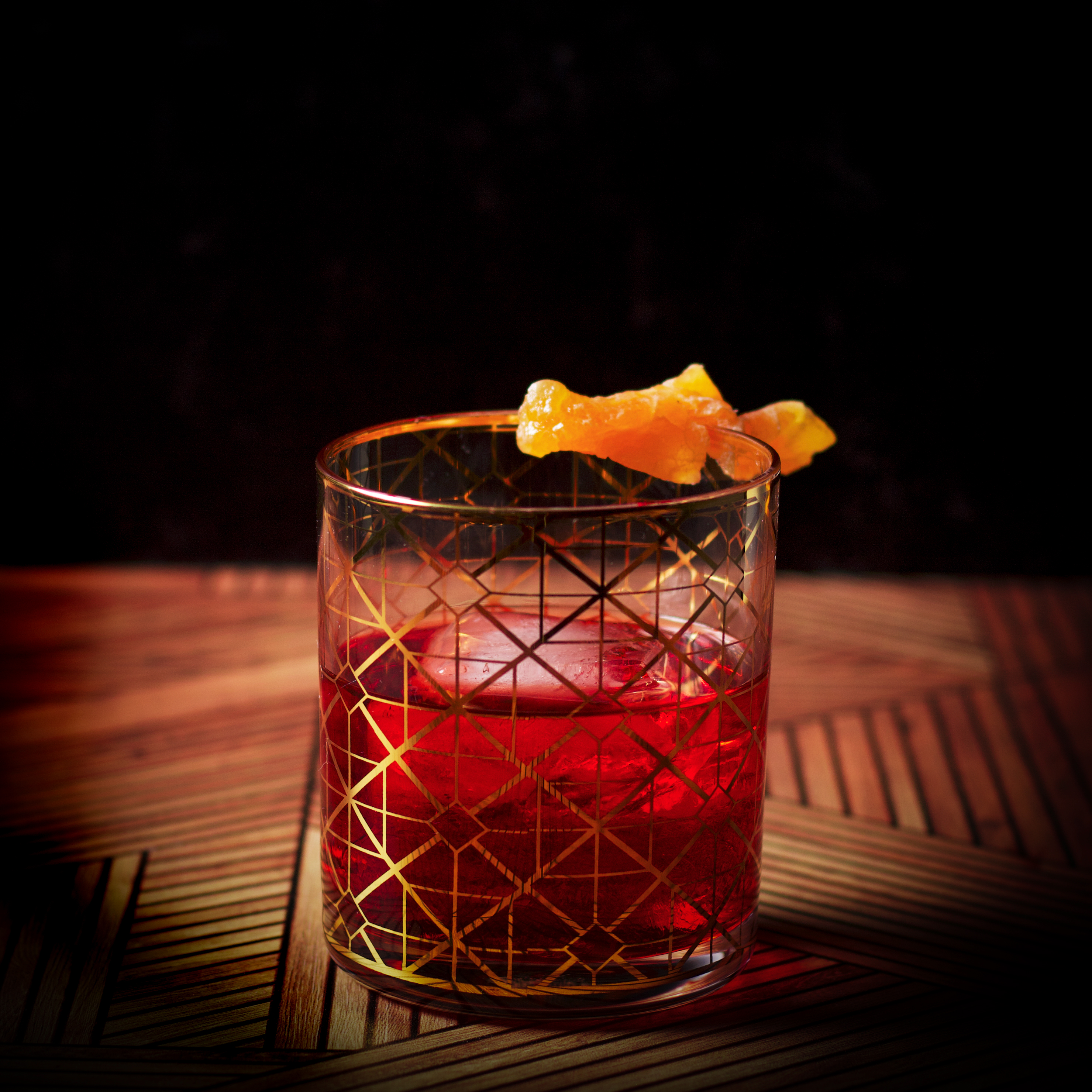 A Boulevardier cocktail, served in a cocktail glass over ice and garnished with an orange twist.