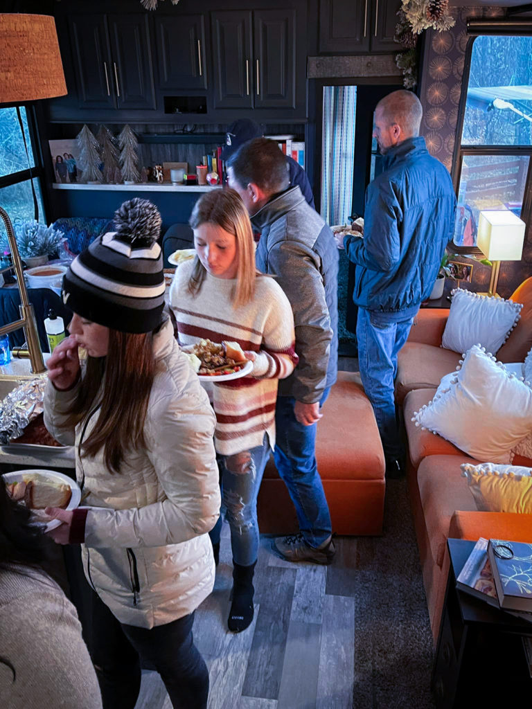 A group of people inside an RV loading up their plates with food on Thanksgiving.