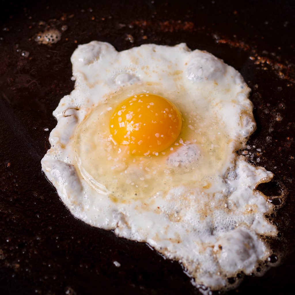 A fried egg cooking in a frying pan.