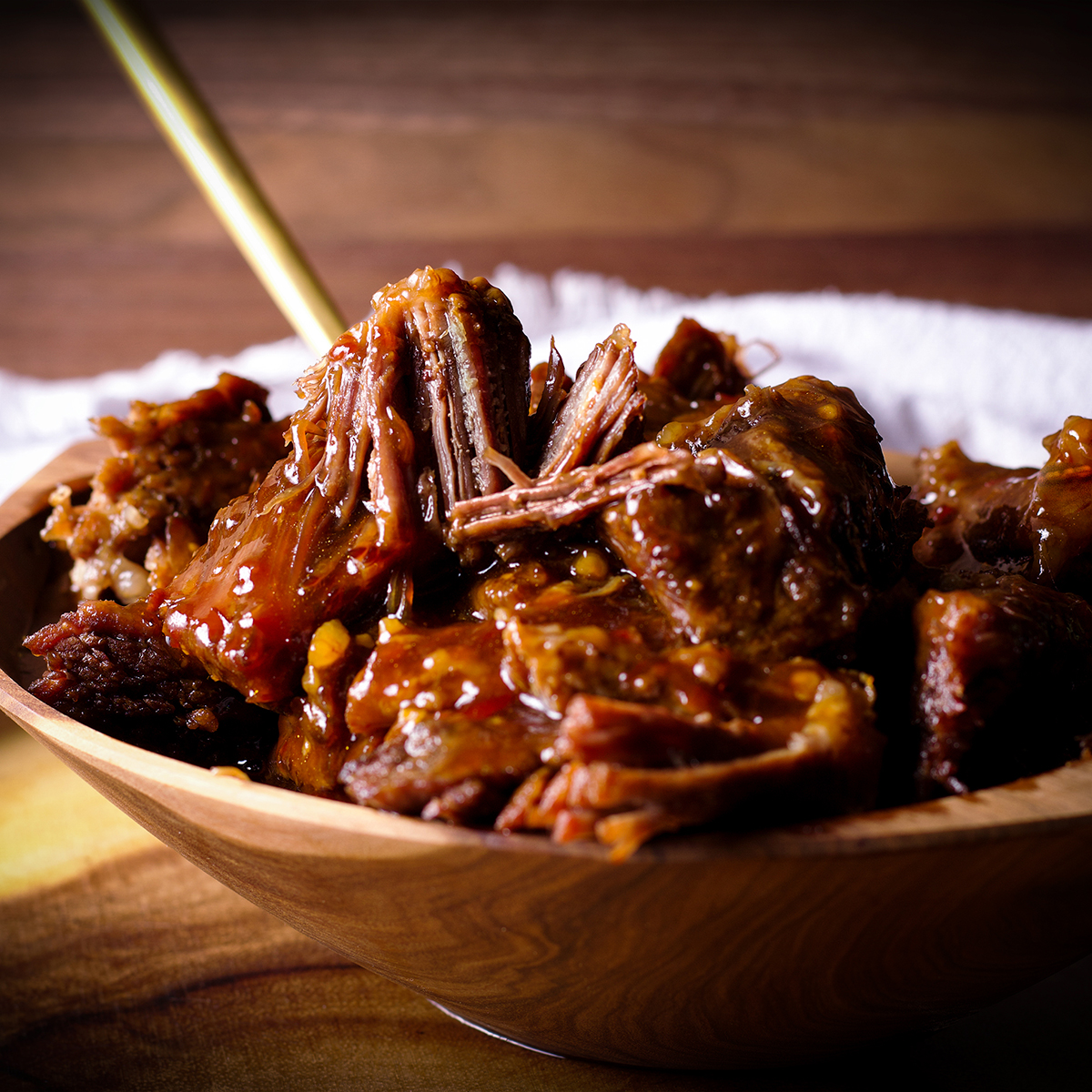A wood bowl filled with warm, tender Asian Short Ribs.