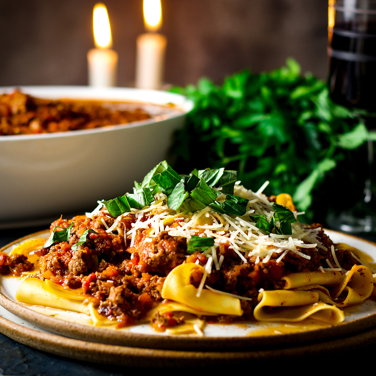 A plate of pasta covered in bolognese sauce and grated parmesan cheese.