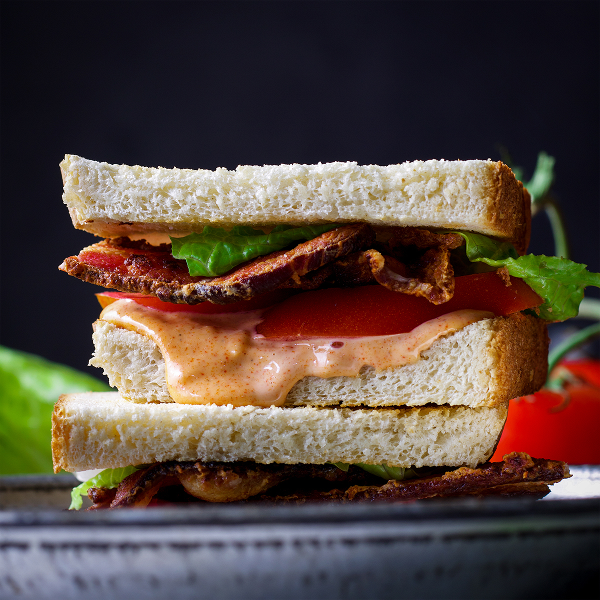 Two halves of a BLT sandwich on a plate, ready to eat.