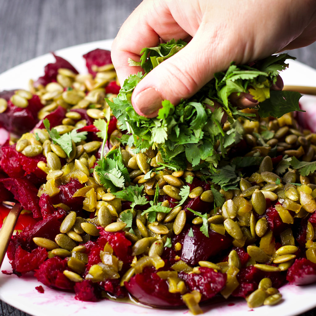Sprinkling fresh cilantro over a plate full of simple roasted beets.