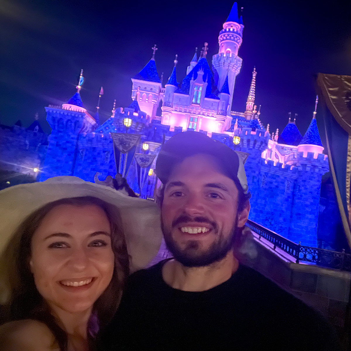 Annie and Scott standing in front of the Cinderella castle at night.