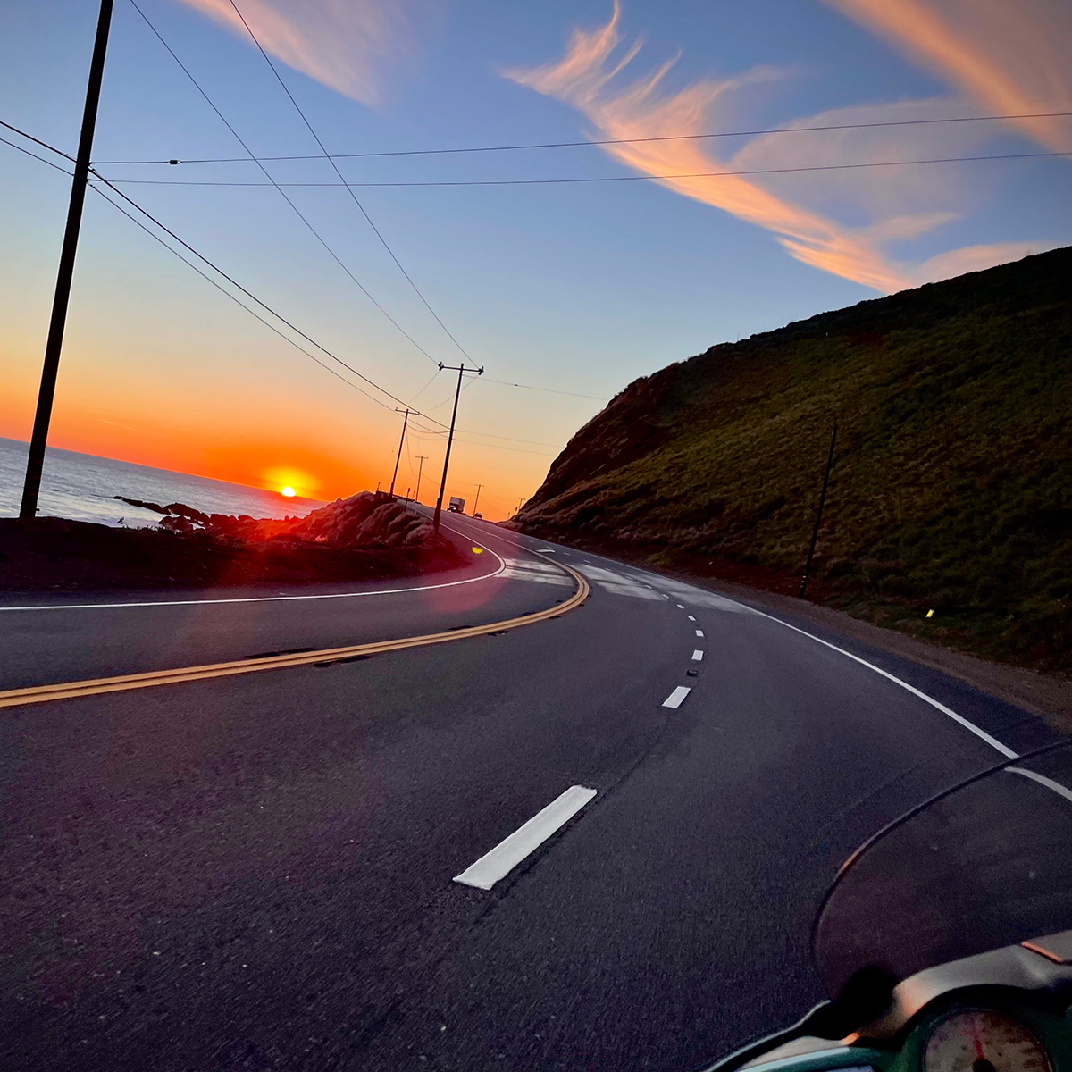 Riding a motorcycle along the California coast at sunset.