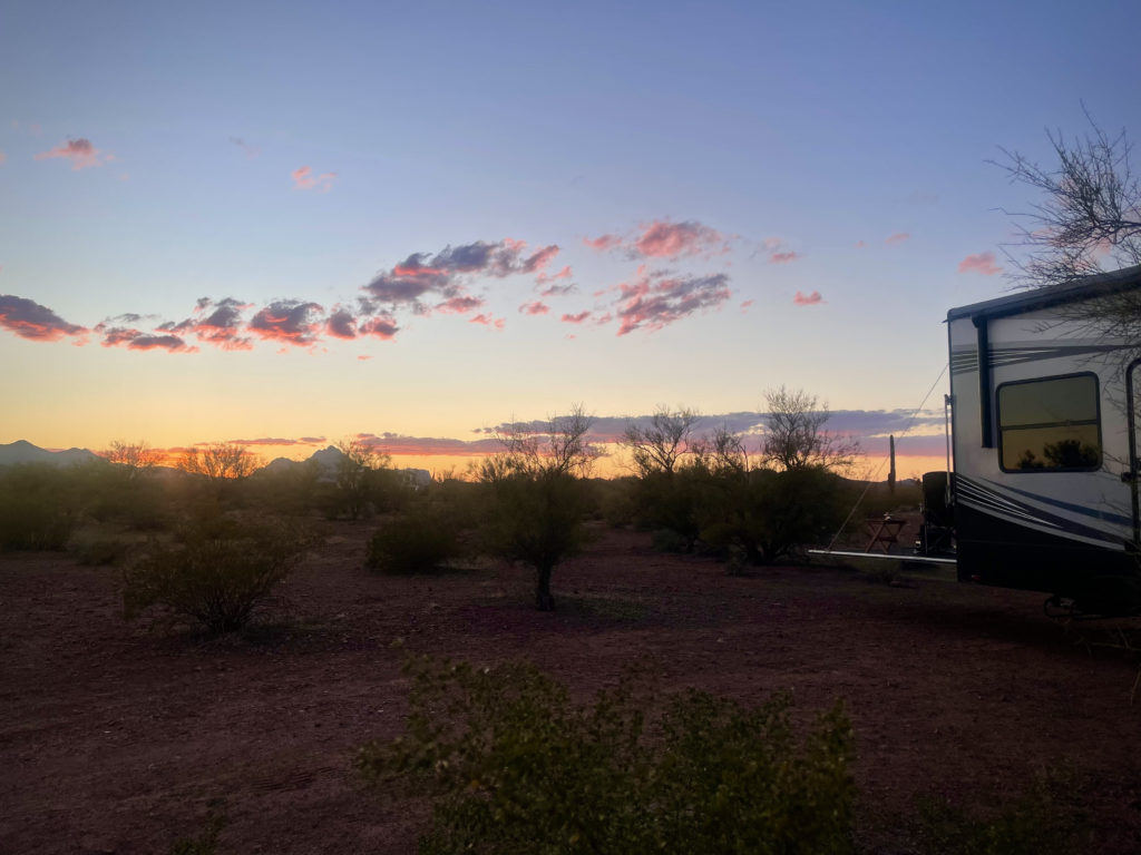 Our 5th Wheel RV parked in Ironwood Forest National Monument with the sun setting in the background.