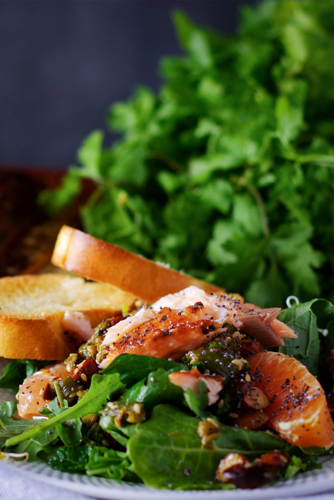 A plate piled high with salmon salad with citrus vinaigrette and almond salsa and a couple of pieces of toasted bread.