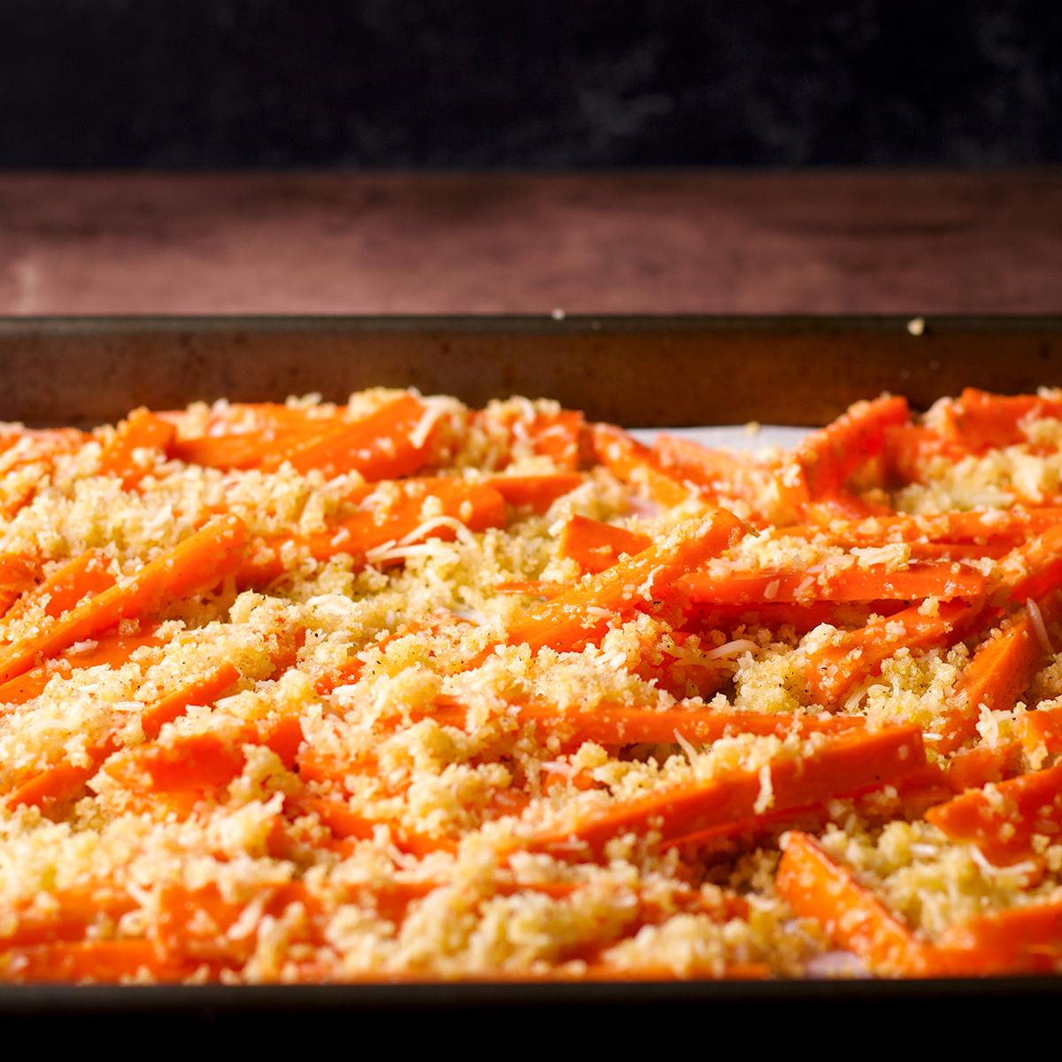A baking tray filled with carrot fries that are ready to be baked.