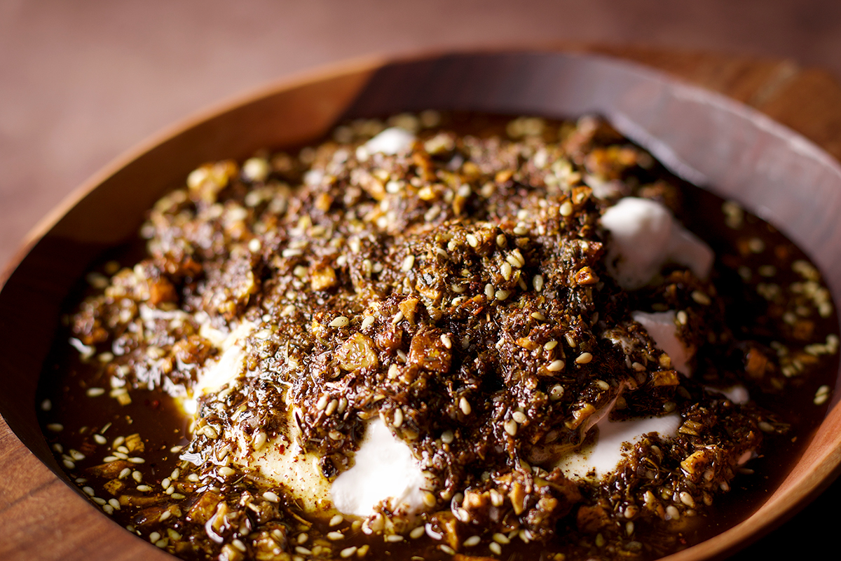 A wood bowl filled with za'atar labneh with crispy garlic.