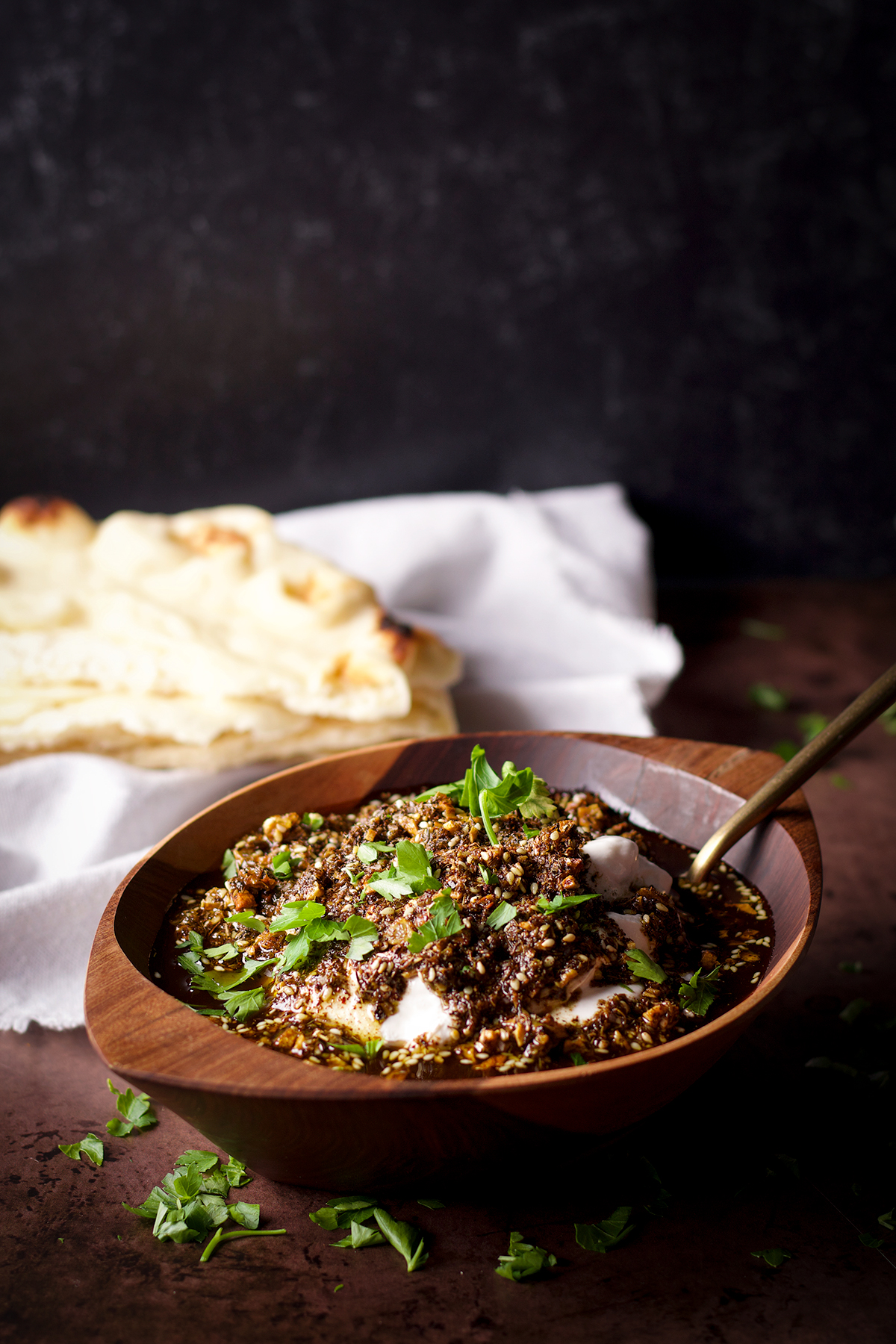 A wood bowl filled with za'atar labneh sitting next to a stack of buttered naan.