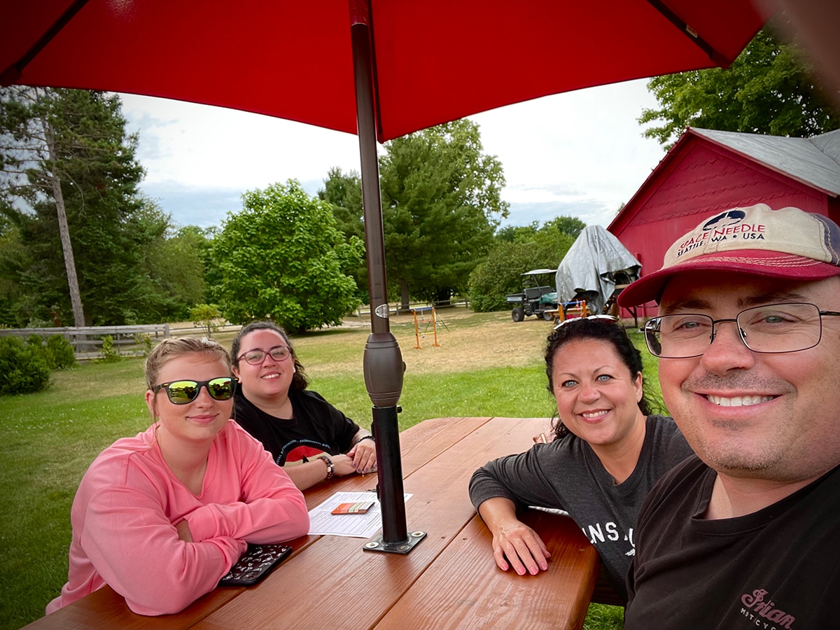 Steve and I with our daughter and niece sitting at a picnic table at St. Ambrose Cellars in Beulah, Michigan.