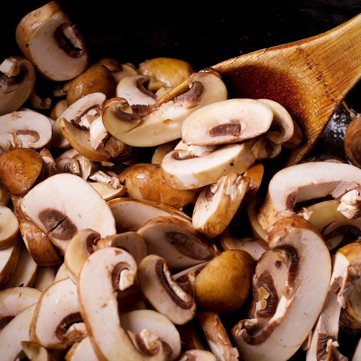 Sliced mushrooms cooking in a dutch oven.