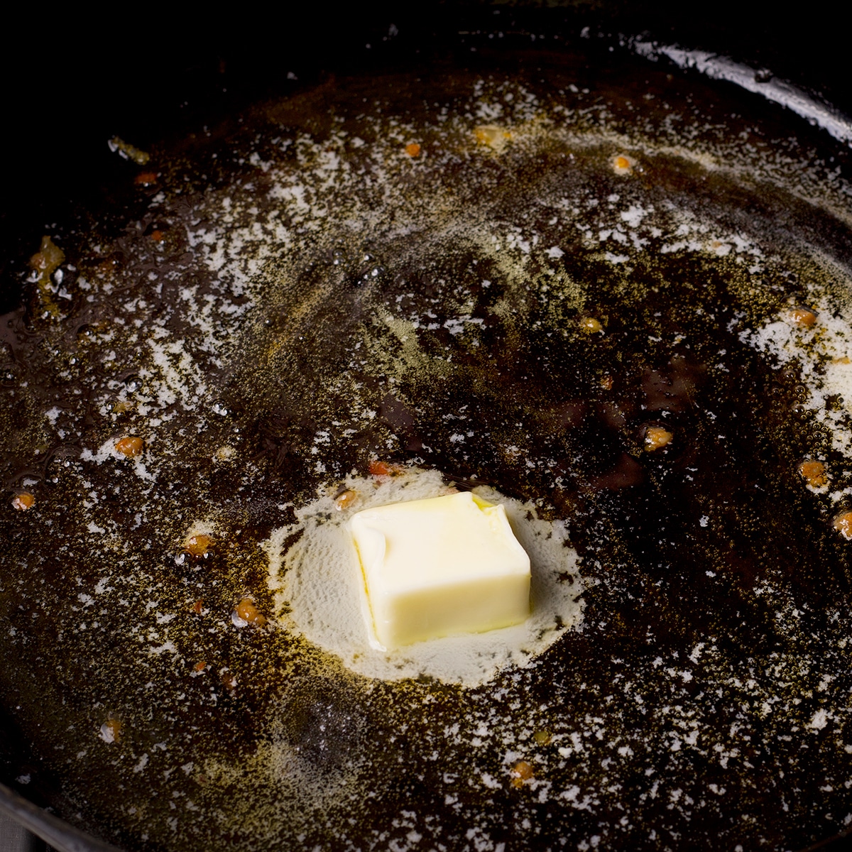 Butter beginning to melt in a cast iron skillet.