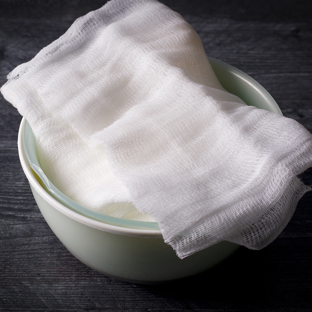 Yogurt wrapped in cheesecloth and set inside a strainer that's set inside a bowl.