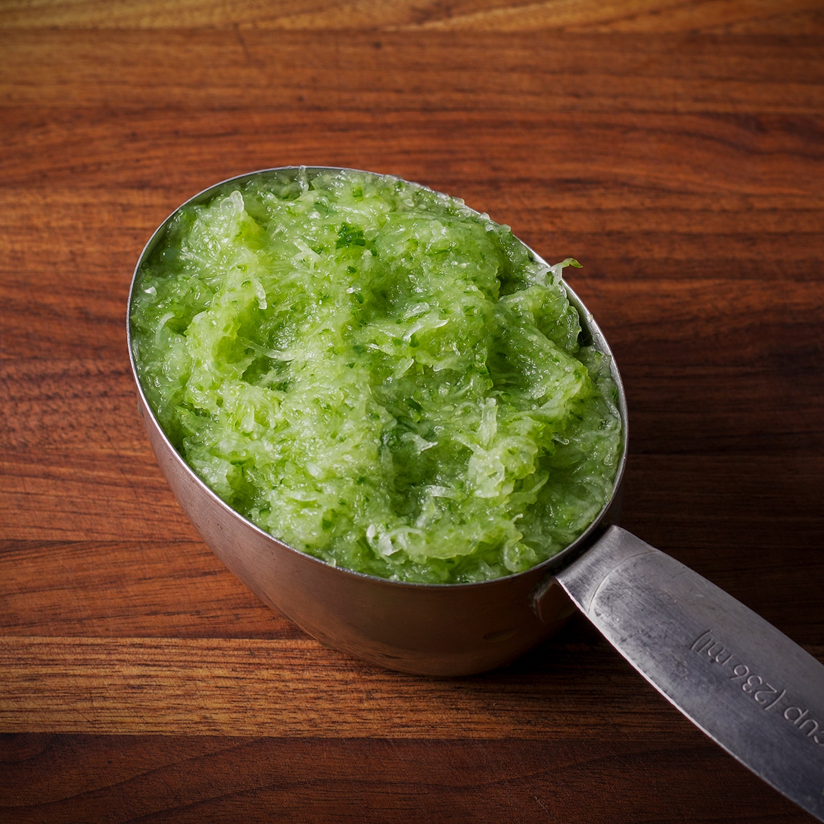 A one-cup measure containing grated cucumber.