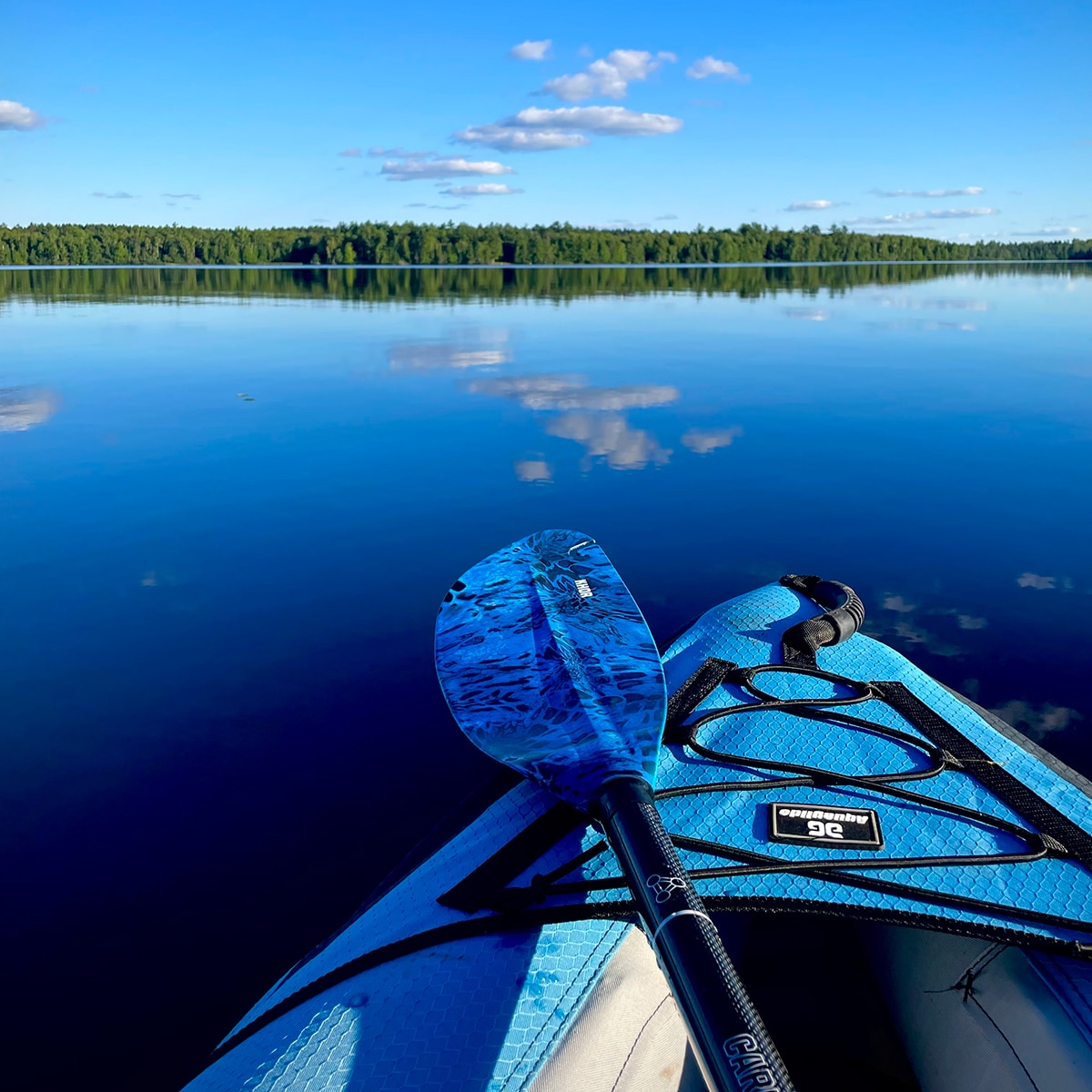 Kayaking across day lake. The lake is so calm it shows a perfect reflection of the sky.
