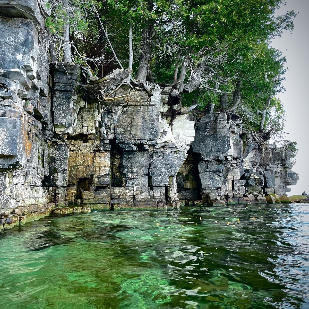 Kayaking past rocky cliffs along the Green Bay shore of Door County.