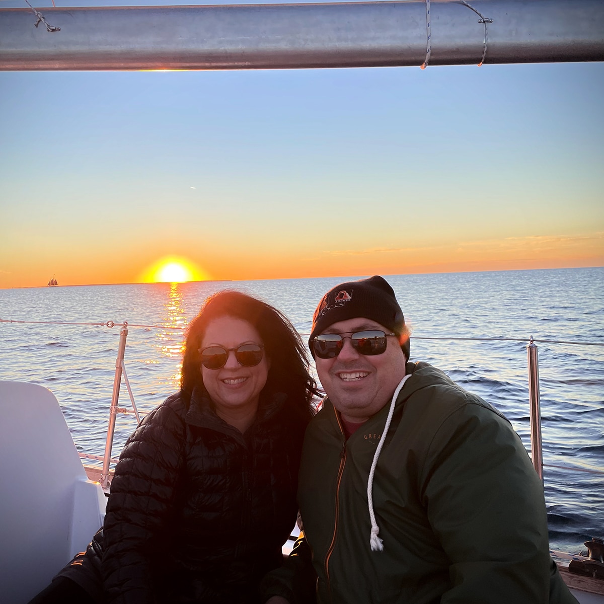 Steve and Rebecca Blackwell on a sailboat in Door County, Wisconsin with the sun setting in the background.