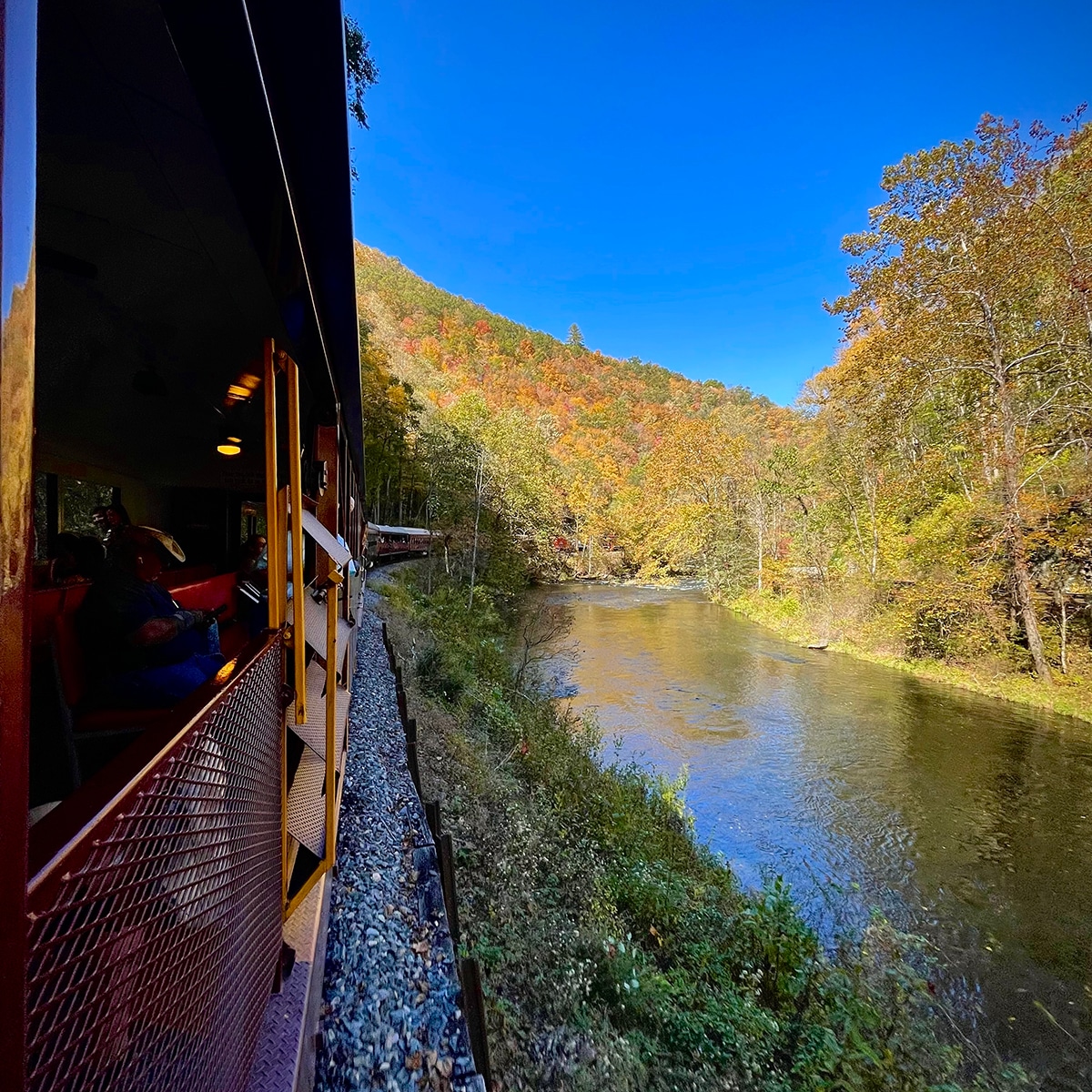 Looking out the open window of the Great Smoky Mountain Railroad to view the back of the train as it rides along the Nantahala River.