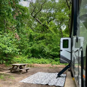 Our 5th wheel RV parked in a wooded spot at Indiana Dunes State Park.