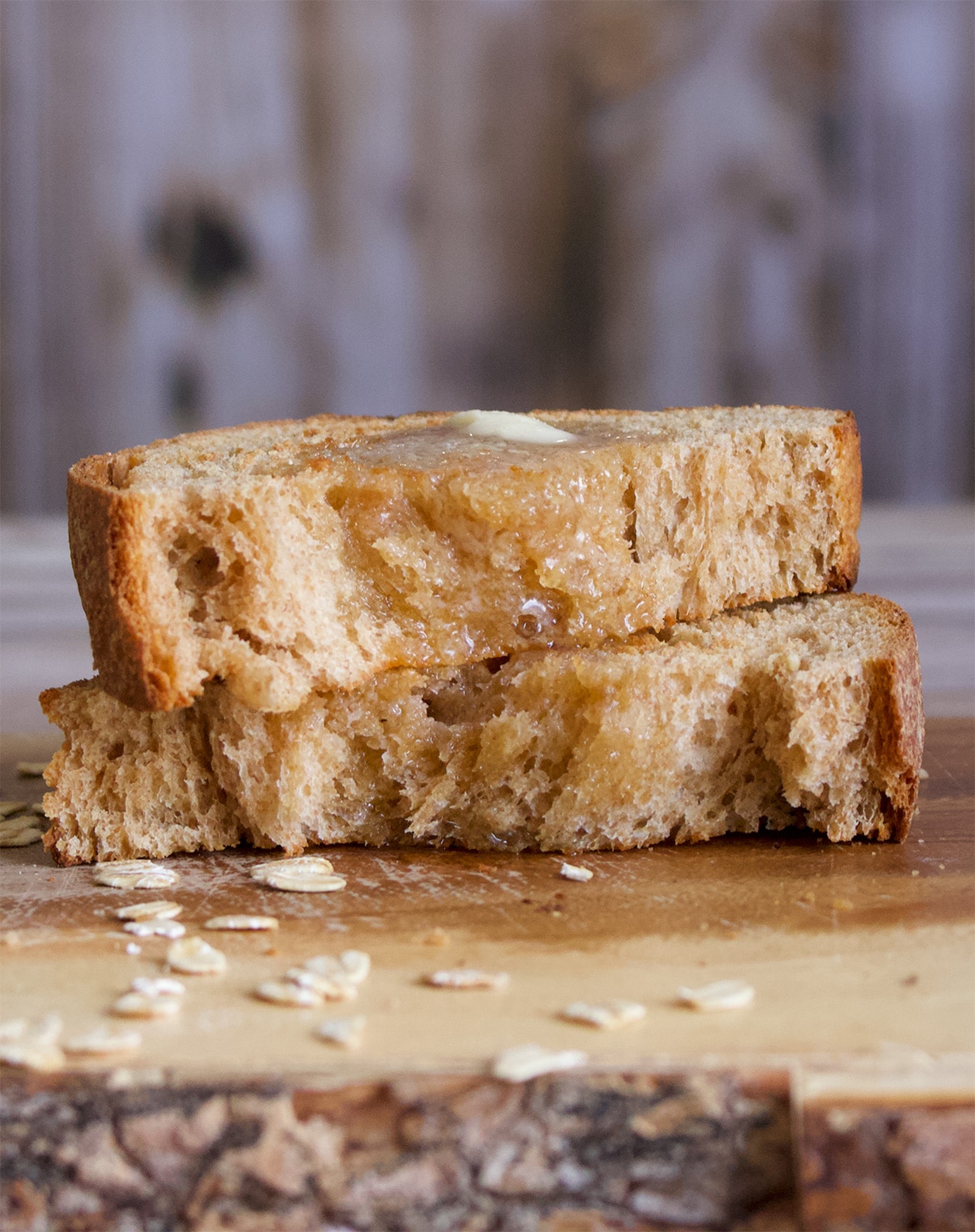 A slice of homemade whole wheat bread slathered with butter.