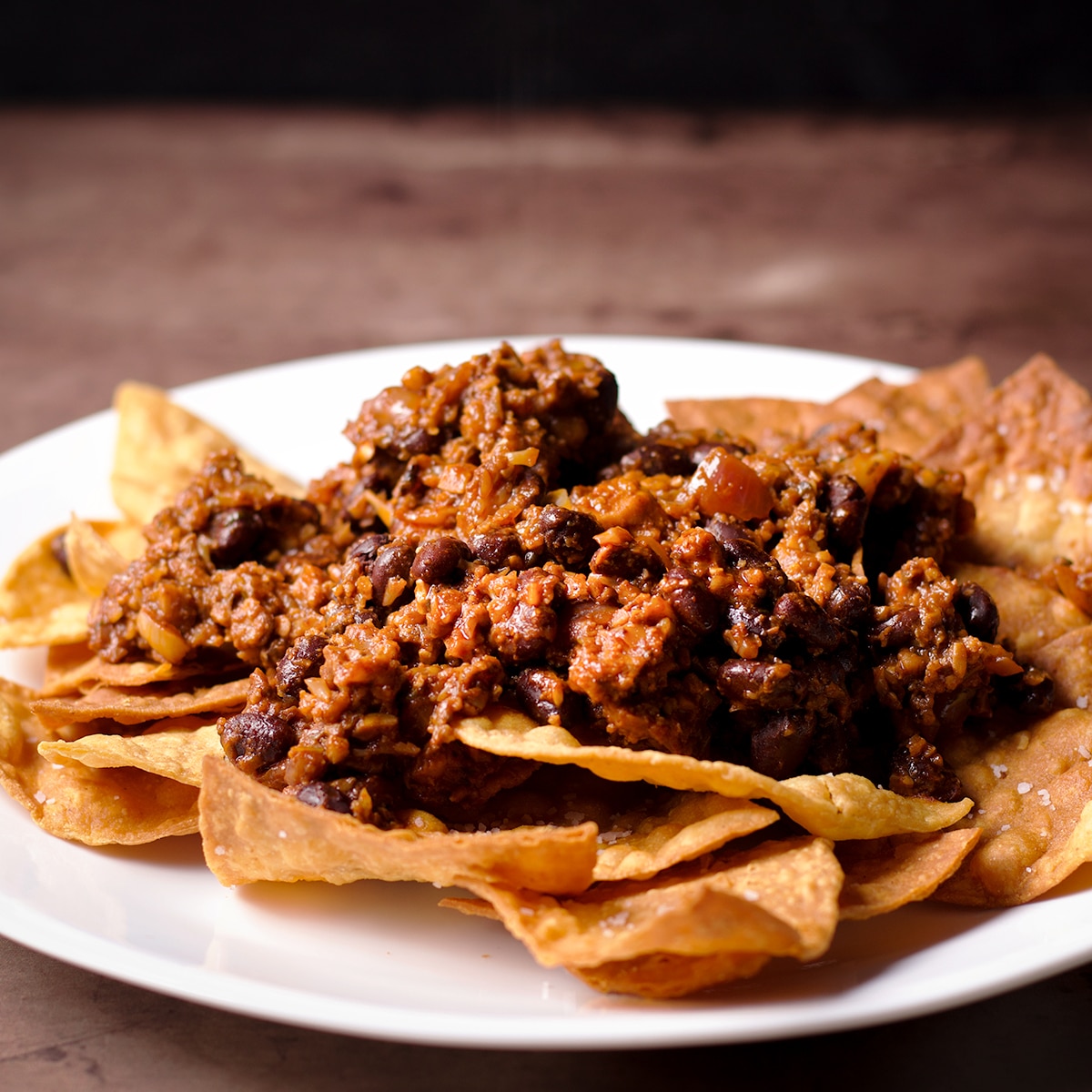 A plate of tortilla chips topped with vegan taco meat.