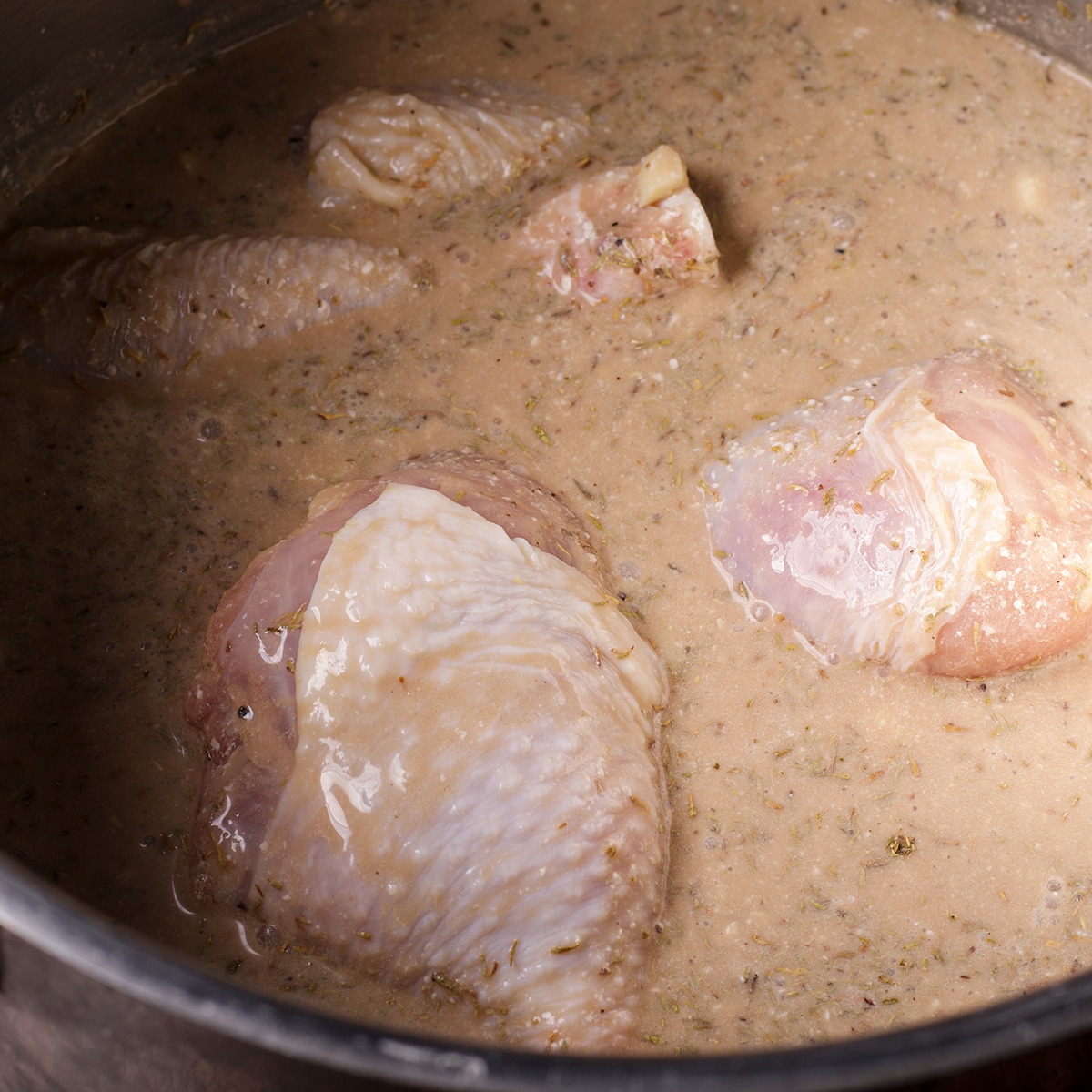 Chicken simmering in coconut adobo sauce.
