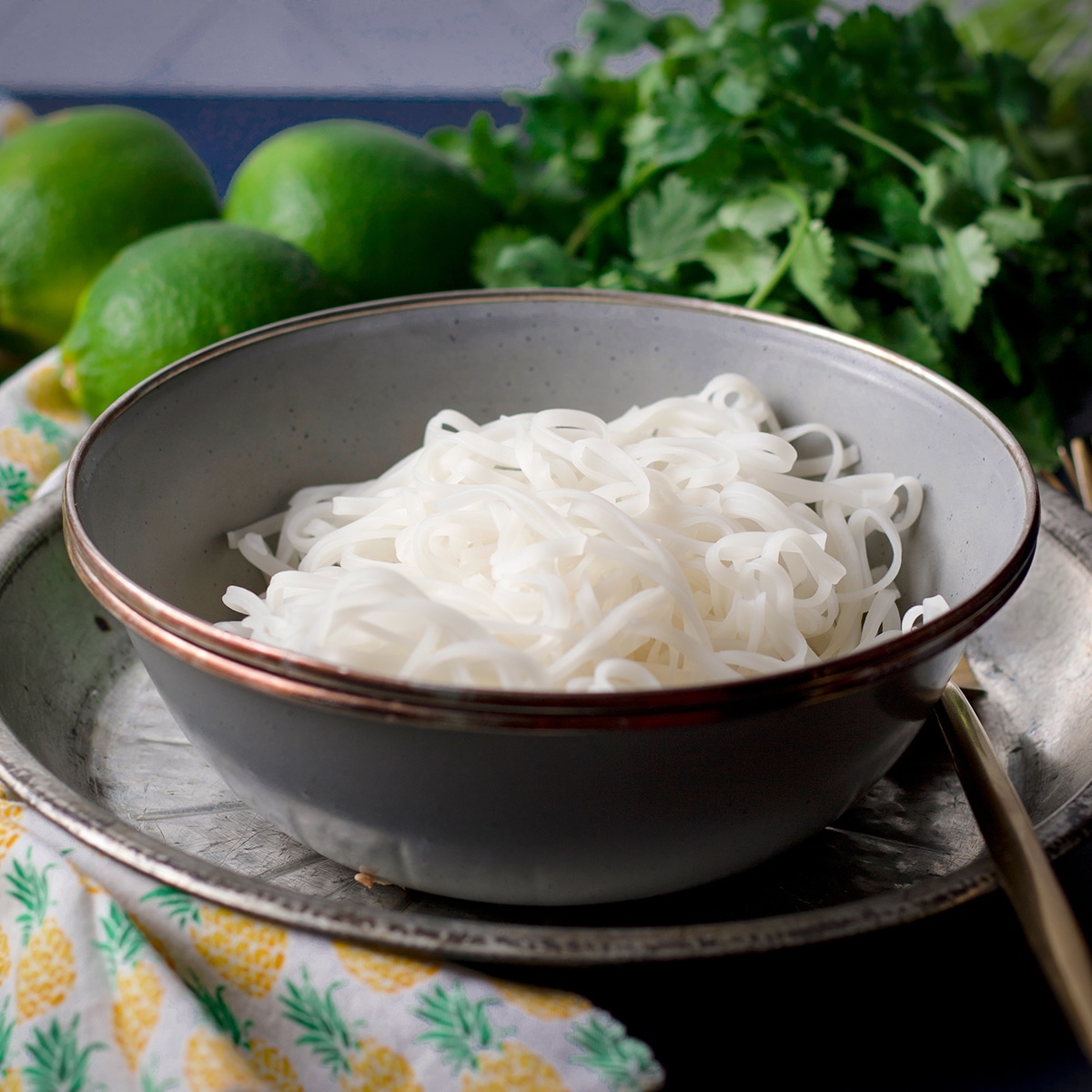 A blue bowl filled with pad Thai rice noodles.