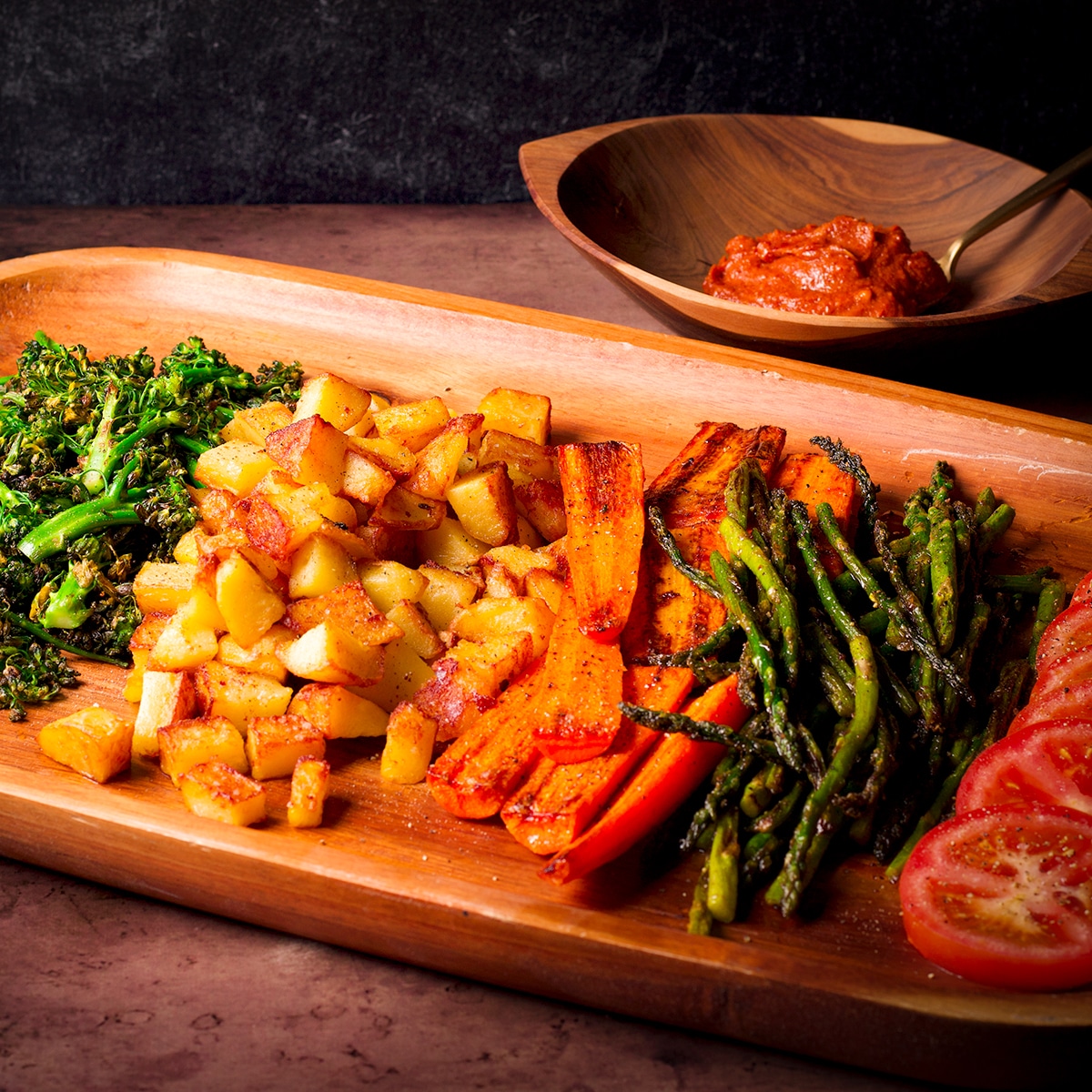 A tray of roasted vegetables sitting on the table next to a bowl of miso butter.