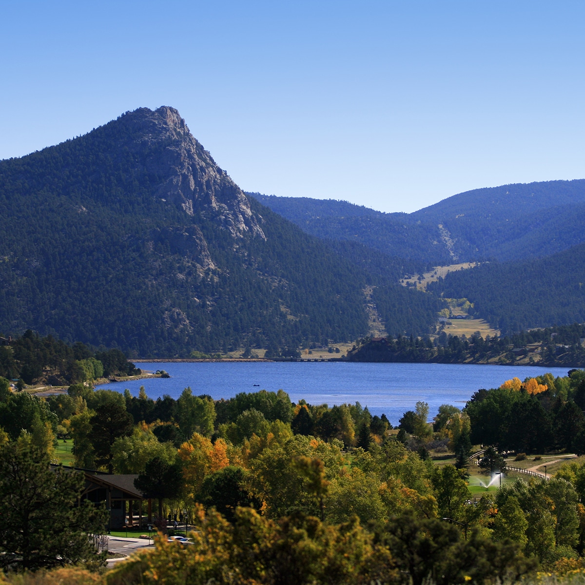 Lake Estes in Estes Park Colorado on a sunny day without any clouds in the sky.