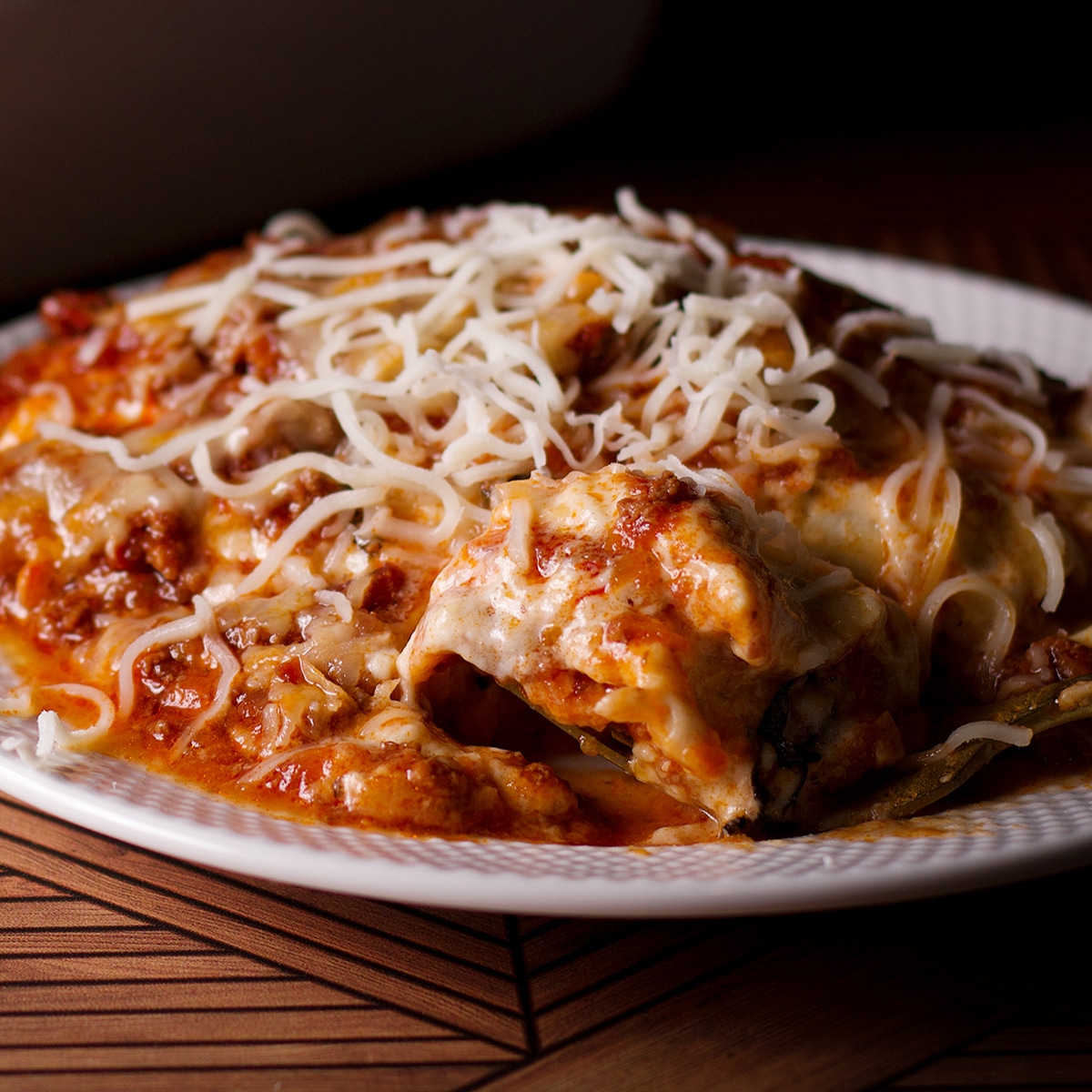 A serving of lasagna bolognese made with parmesan béchamel sauce on a white plate.
