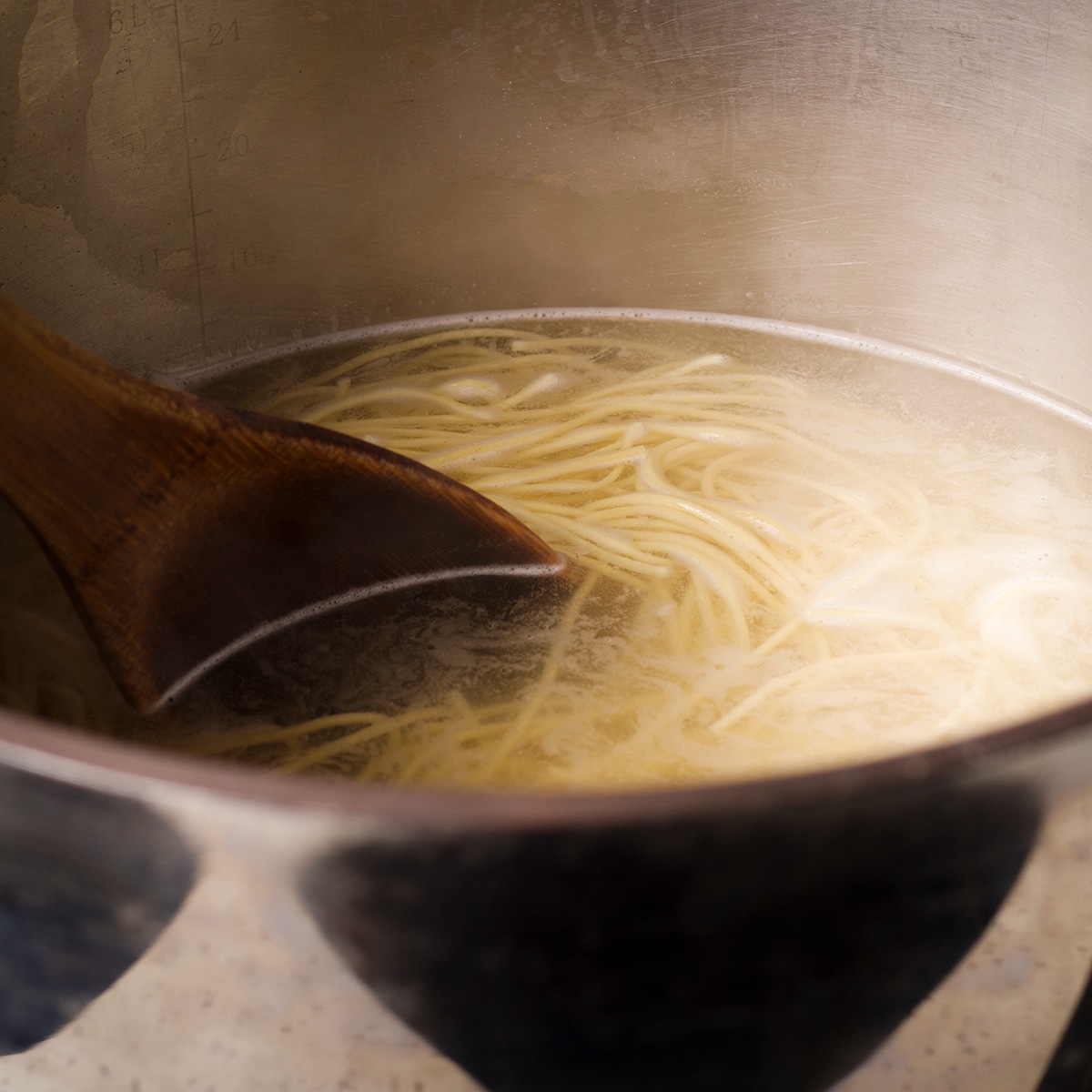 Spaghetti noodles simmering in a pot of salt water.
