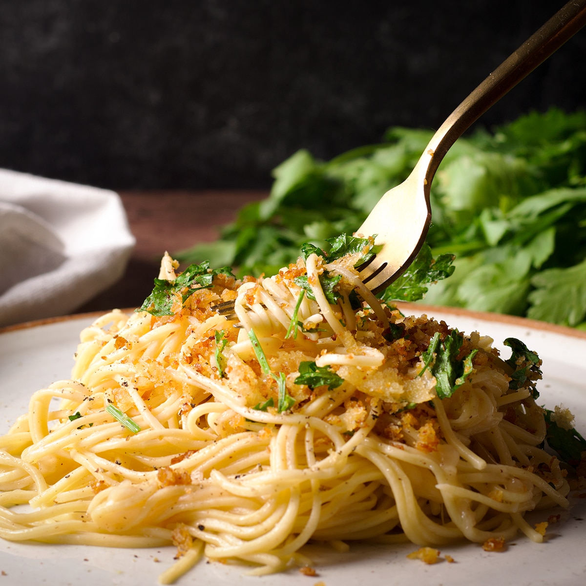 Using a fork to take a bite of brown butter sauce pasta with crispy bread crumbs.